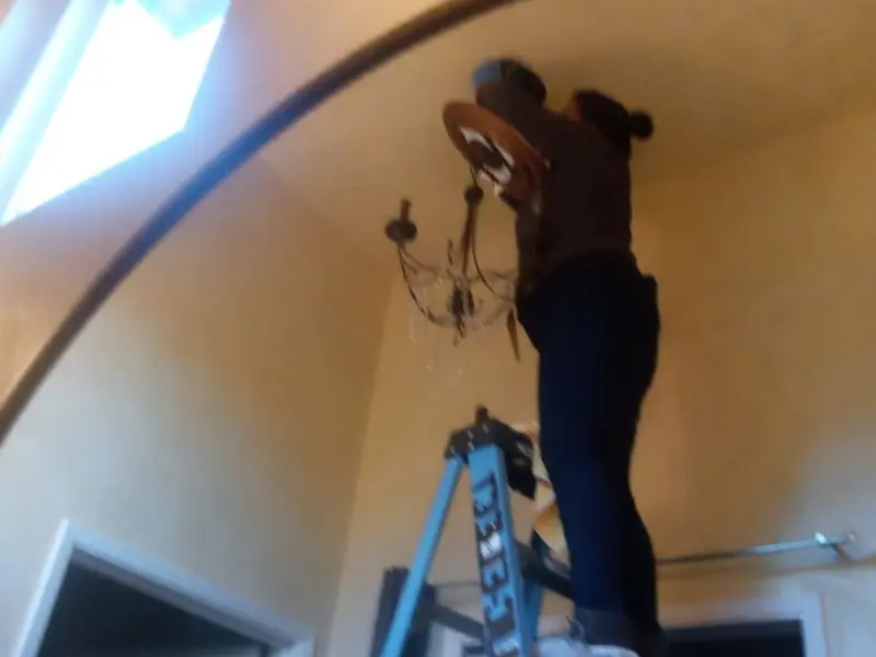 Electrician installing a chandelier in a Stafford residence